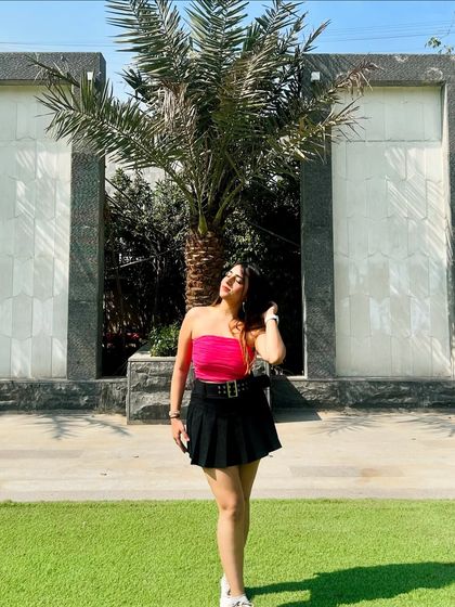 A bright and bold look with a hot pink tube top and a black pleated skirt. This outfit is confident and eye-catching.