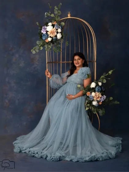 A regal portrait in our elegant birdcage setup. The mom-to-be looks like a queen in a flowing dusty blue gown, surrounded by beautiful floral arrangements.