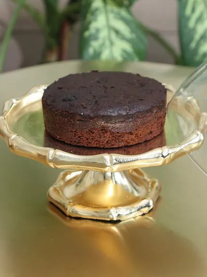 The Cakescape, our gold dessert stand with a scalloped edge, showcasing a rich chocolate cake. Its timeless design makes it a perfect centerpiece for any celebration.