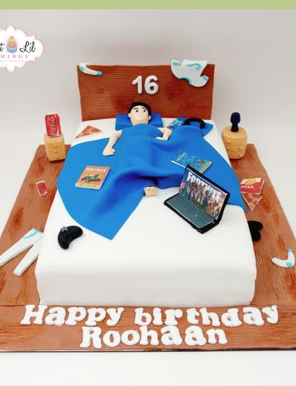 A detailed gaming-themed cake for Roohaan's 16th birthday, depicting him relaxing in bed while playing Fortnite.