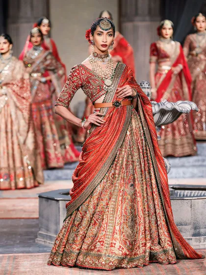 Another powerful shot of the lead model in a red lehenga, commanding the stage. This image is a testament to strong runway photography.