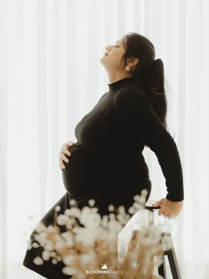A serene and contemplative silhouette in a black turtleneck dress. This shot beautifully captures the quiet strength of motherhood.