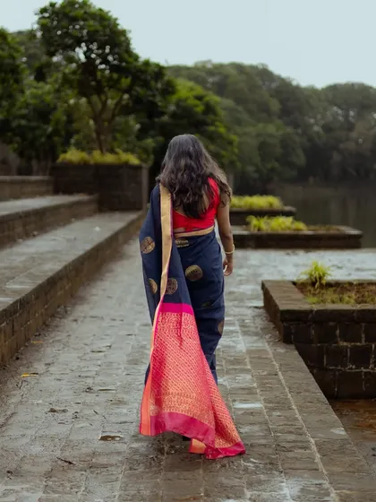 This shot captures the movement and beauty of the saree from behind. As the model walks away, the vibrant pink pallu trails behind her, creating a visually striking image full of color and motion.
