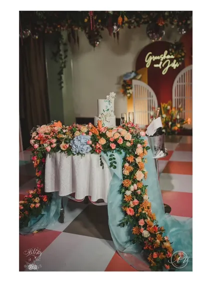 A full view of the cake table, adorned with a lush river of flowers that matches the overhead installation, creating a cohesive and stunning look.