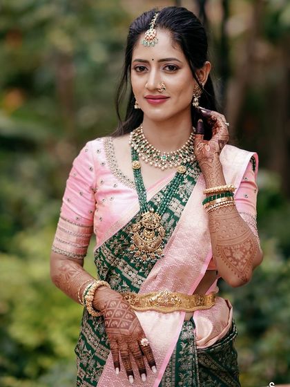 A close-up of bride Ankita, showing the delicate embroidery on her pink blouse which pairs beautifully with her green Kanchivaram and temple jewelry.