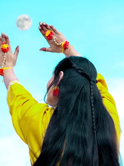 A creative and playful shot from a mehndi ceremony, with the bride-to-be reaching for the moon.