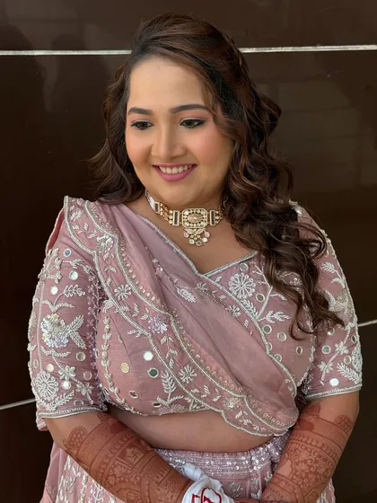 A smiling portrait of the bride, looking radiant in her soft glam baraat look. The makeup is designed to look beautiful in natural light.