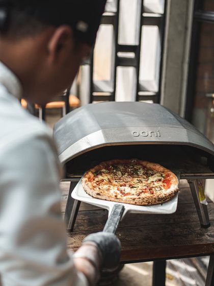 A perfectly cooked pizza emerges from our Ooni pop-up oven. This setup is ideal for backyard parties, apartment gatherings, or any event where space is a consideration.