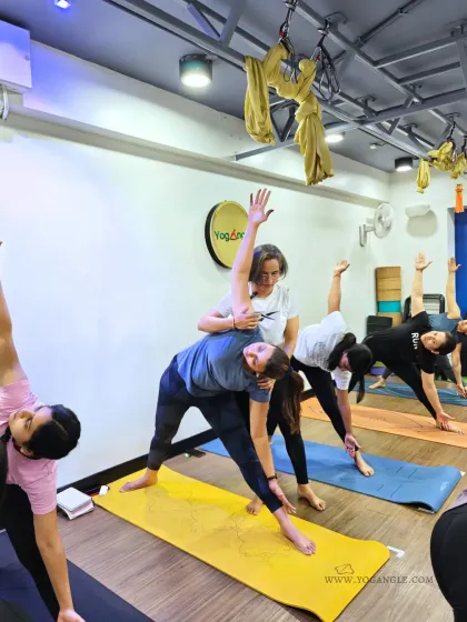 During our workshops, I ensure every participant receives personal attention. Here, an instructor provides a gentle adjustment in Trikonasana (Triangle Pose) to help a student find more space and alignment.