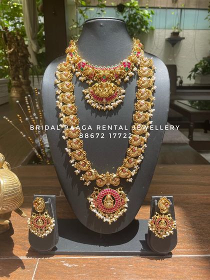 A classic Kemp stone bridal set. This rental piece features a choker and a matching long haram, both adorned with vibrant red stones and pearl droplets.