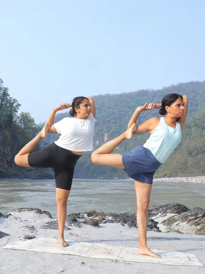 A mother-daughter team of yoga teachers. We practice Natarajasana, or dancer's pose, by the serene river.