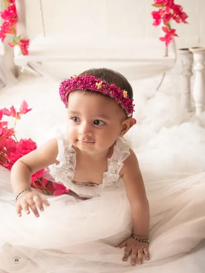 A close-up of the younger sister during the sibling shoot, looking curious and sweet amidst the bright pink flowers.