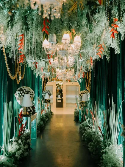 This is what I call moody luxe. I designed this dramatic entrance with deep green velvet drapes, a ceiling dripping with white florals and crystal chandeliers, and warm, focused lighting. It’s about creating an immersive, theatrical experience from the moment guests arrive.