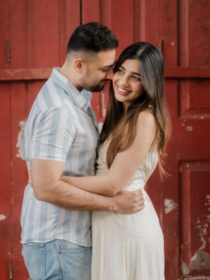 An unposed, genuine moment of affection. The vibrant red door provides a beautiful pop of color, highlighting the couple's easy chemistry.