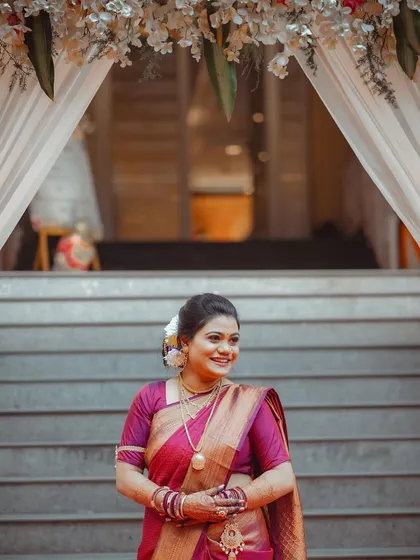 The bride's happy smile as she stands under a floral archway. This portrait is full of light and joy, perfectly capturing the wedding day atmosphere.