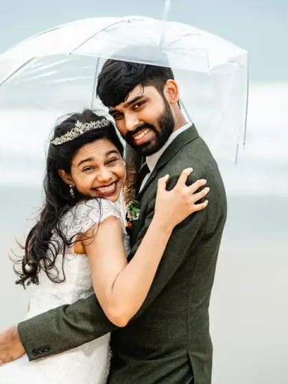 A candid moment of happiness during a rainy Goa photoshoot. The genuine smiles and warm embrace under the umbrella show that even a little rain can't dampen the joy of the day.