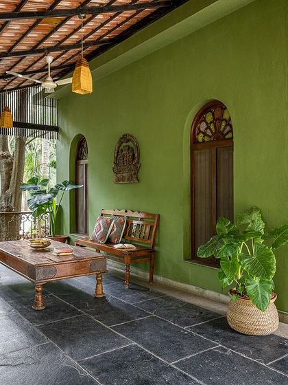 The veranda of the Vasishta suite, with antique wooden furniture and views of the surrounding greenery.