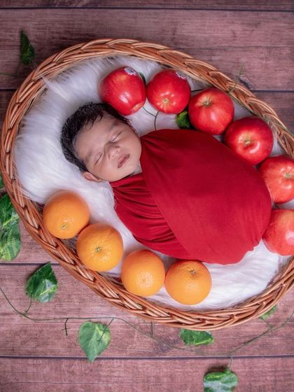 The apple of my eye. This fun setup combines a classic red swaddle with fresh fruits for a colorful and unique newborn photo.
