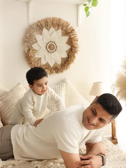 A playful moment on dad's back. This image from a lifestyle session captures the fun and casual bond between a father and his son. The natural, home-like setting makes the moment feel authentic and warm.