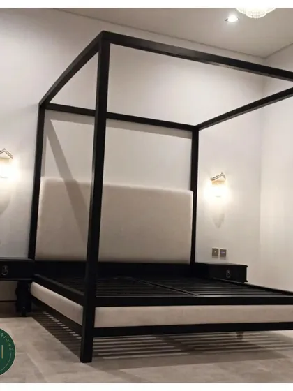 A striking four-poster bed in a black finish with a contrasting cream-colored upholstered headboard and base. This piece combines classic form with a modern, high-contrast color palette for a dramatic effect.