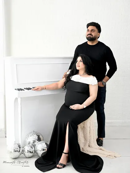 A sophisticated couple's portrait by the white piano. The classic black outfits and clean white background create a modern and elegant look.