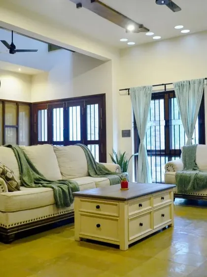 A wider view of the living area, showing the open-plan layout that connects to the dining space. The polished Jaisalmer stone flooring adds a warm, earthy tone.