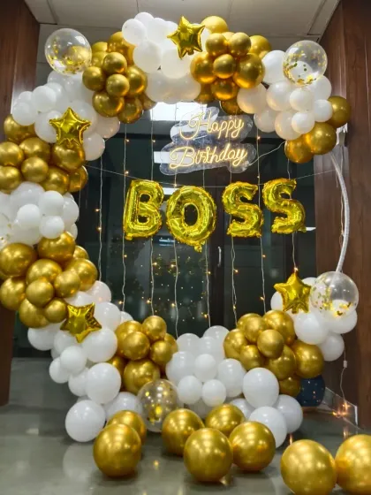 A special birthday setup for the 'BOSS'. This gold and white balloon ring includes 'BOSS' foil letters and a neon sign, perfect for an office celebration.
