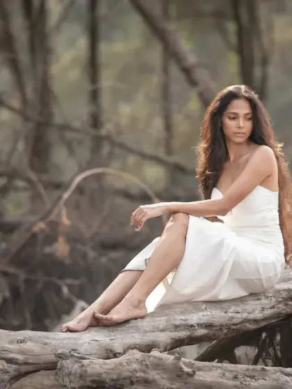 An editorial bridal portrait in a rustic, wooded setting. The pose and the raw natural backdrop create a powerful and earthy image.