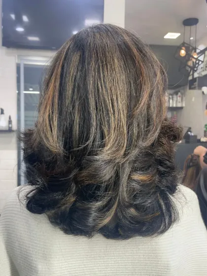 The back view of a voluminous, layered haircut with subtle highlights. The inward-curled ends create a classic, polished finish.