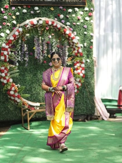 A full-length shot of the bride in her Nauvari saree, looking confident and stylish against a beautiful floral backdrop.