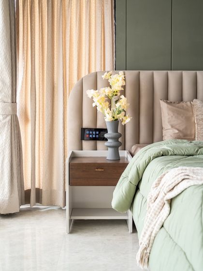 A close-up of our design for a parents' bedroom, featuring a custom side table in high-gloss PU. The space is designed with muted tones and pastel green hues to exude understated elegance and warmth, with every element curated to nurture peace.