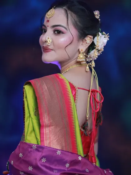 A side profile of a student's work on a Maharashtrian bride, highlighting the intricate hairstyle with flowers.