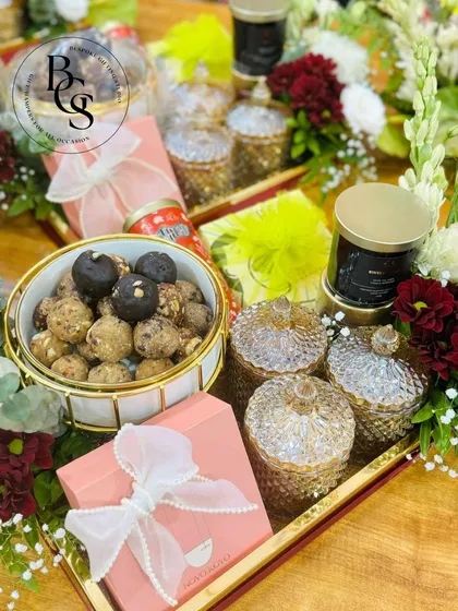 This elegant tray hamper is a beautiful example of a wedding or engagement gift. It features crystal jars, artisanal sweets, and scented candles, all arranged with fresh flowers for a luxurious presentation.
