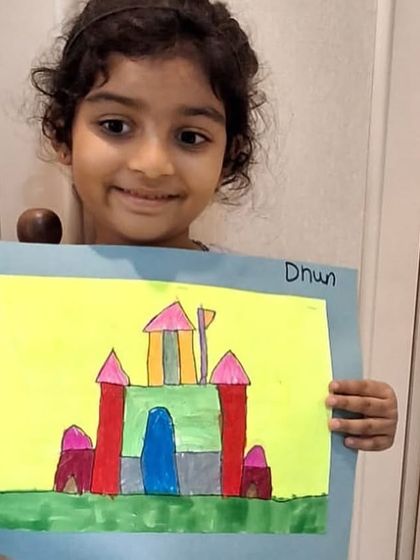 This student is delighted to display her colorful castle, a piece she created from start to finish on her own.