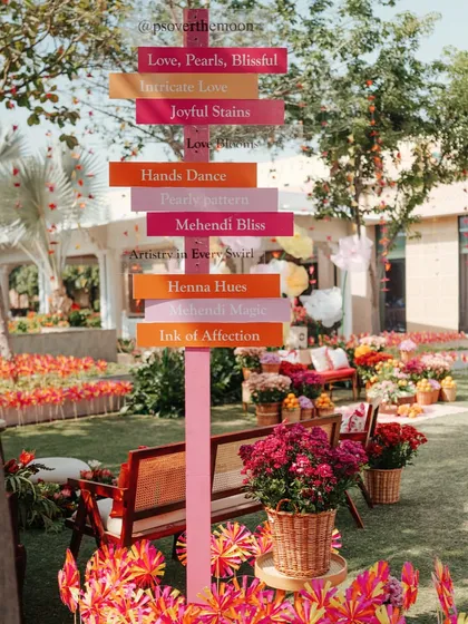 A playful directional signpost with phrases related to the Mehendi ceremony, like "Henna Hues" and "Mehendi Bliss," adding a personalized and fun touch to the decor.