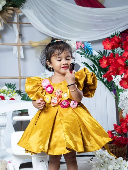 This little girl is looking beautiful in her puffy yellow dress, ready for a party.