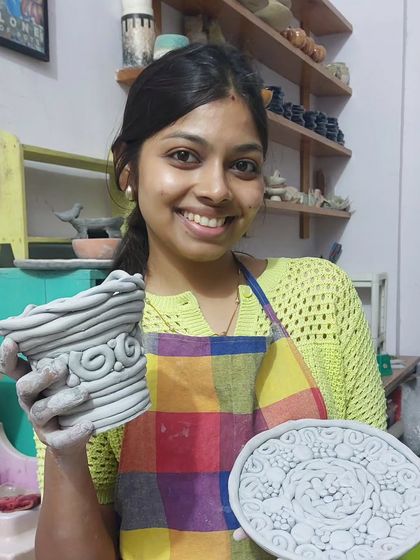 Look at that happy smile! This student is holding up her textured pot and intricately designed plate. It's always heartwarming to see the joy and sense of accomplishment when students see what they've made with their own two hands.