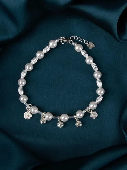 A pearl bracelet with dangling silver bell-shaped charms.