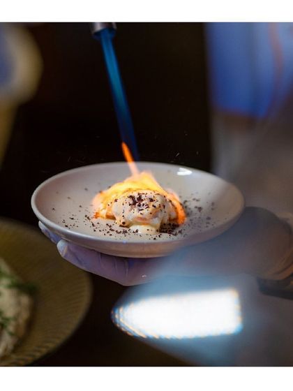 We love creating exotic and theatrical food experiences. Here, a dish is being finished with a blowtorch, adding a touch of fire and drama right at the table.
