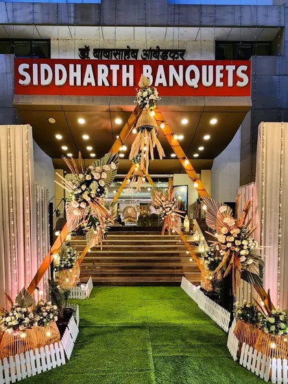 A unique teepee-style entrance for a boho-themed engagement. The wooden structures are decorated with pampas grass and floral arrangements, creating a rustic and welcoming entryway.