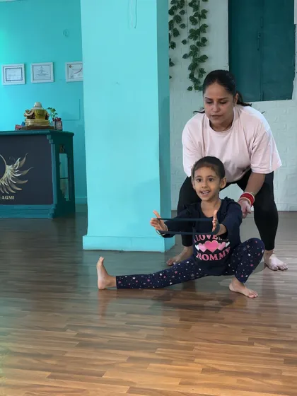 Using a resistance band for a squat stretch, this student gets my support to keep her posture upright and her form correct. This builds strength in her legs and core simultaneously.
