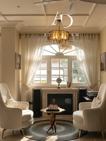 This cozy seating nook features vintage-style armchairs by a fireplace, creating a perfect spot for conversation or reading, bathed in natural light.