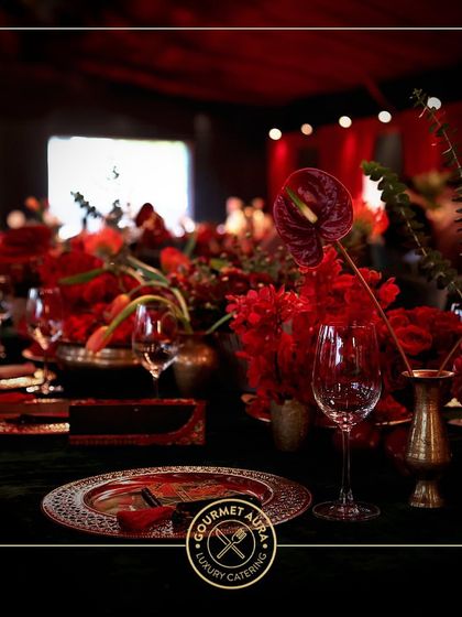 A bold and dramatic table setting with vibrant red floral arrangements and intricate plates. We tailor our presentation to match any theme, no matter how daring.