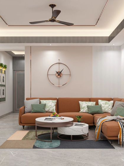 The living room of the Bhagalpur project, featuring a large L-shaped sofa in a warm terracotta color. The design incorporates a gallery wall, indoor plants, and a geometric rug to create a comfortable and personalized family space.