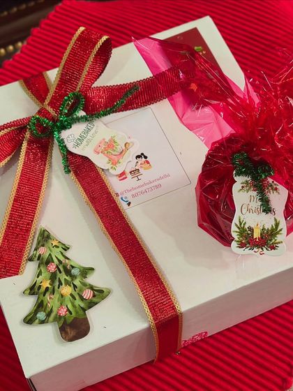 A beautifully wrapped Christmas gift box. We use festive red ribbon and custom tags to make every hamper feel special, like this one containing our rich, homemade plum cake.