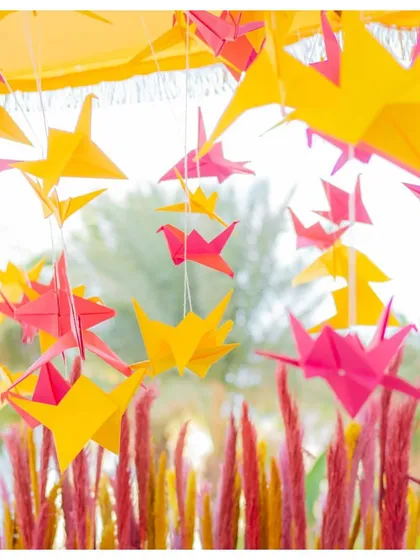 Pink and yellow origami birds suspended from the ceiling added a touch of whimsical, handcrafted charm to this Mehendi decor.