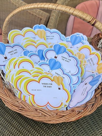 A basket full of "Wishes for the Baby" cards, designed with a hot air balloon theme for a first birthday party.