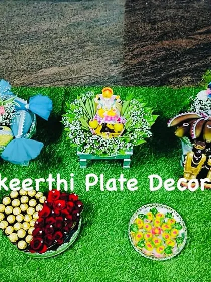 This is a closer look at a set of platters I prepared for an 'Uruthi Varthai' engagement ceremony. The arrangement includes a Ganesha idol for blessings, decorated coconuts, fruits, and sweets, all designed with a consistent blue and green theme.
