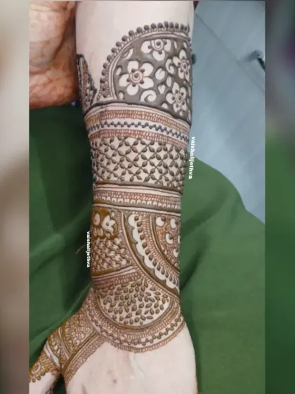 A detailed look at the back of a bride's arm. The design features intricate floral patterns and geometric checks, ensuring beauty from every angle.