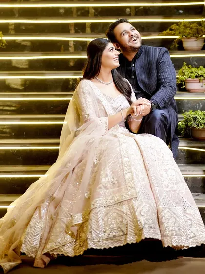 A sweet and candid moment of the couple sharing a laugh on a beautifully lit staircase.